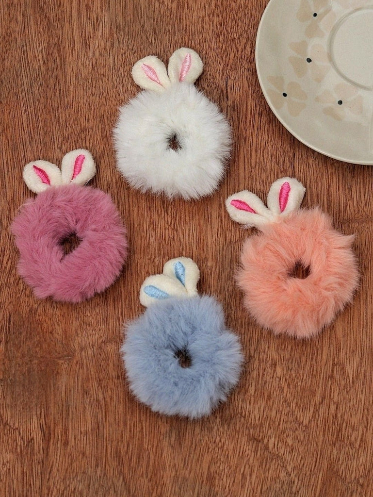 Soft and fluffy bunny ear scrunchies by Yellow Bee, presented on a warm wooden surface, showcasing their plush texture and pastel colors.