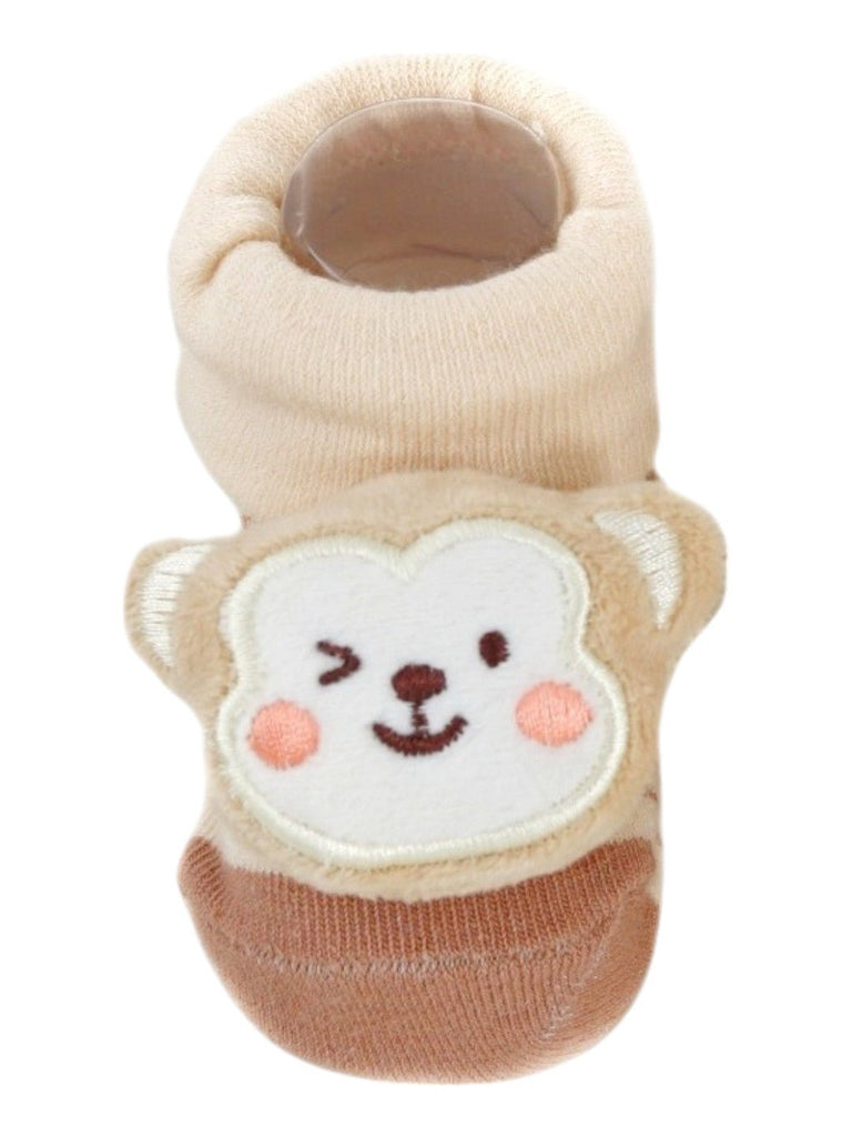 Close-up view of beige baby booties with a fun 3D monkey face, perfect for babies.