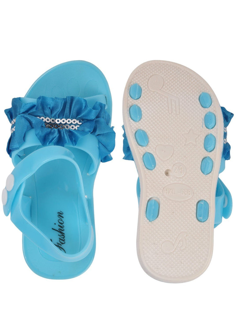 front and back view of blue sandals featuring a ruffled bow and sequin accents.