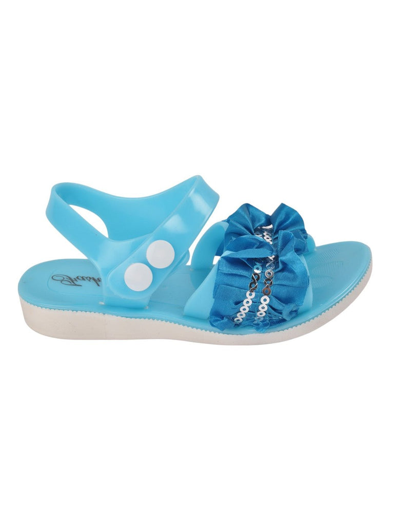 Side view of blue sandals featuring a ruffled bow and sequin accents.