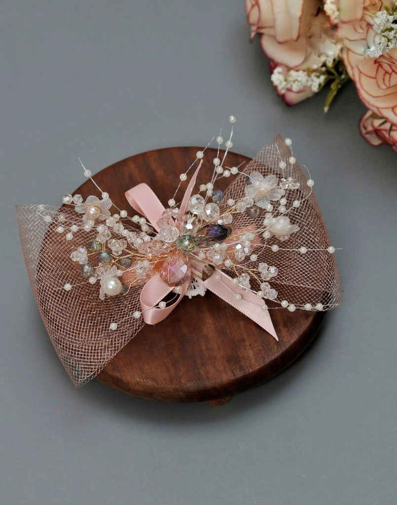 Yellow Bee's peach embellished net bow hair clip presented on a wooden display, highlighting its intricate design and luxurious embellishments.