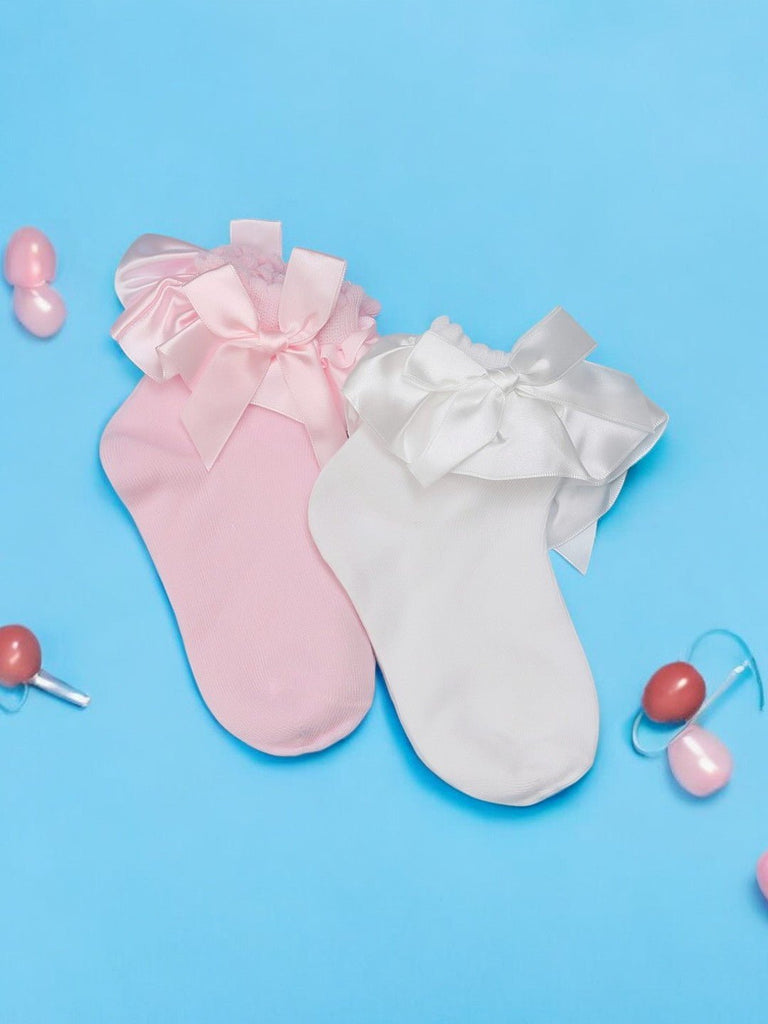 Pink and white baby socks with satin bows, creatively displayed on a blue background with decorative elements.