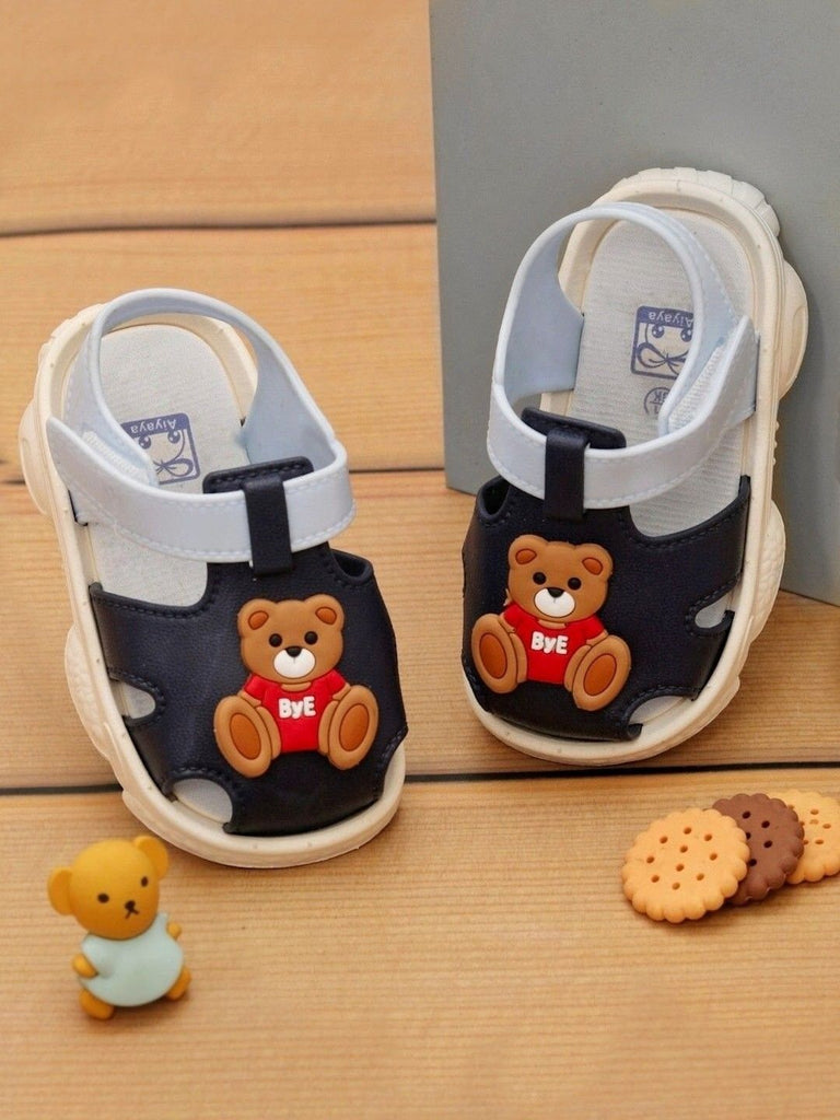 Yellow Bee Teddy Bear Strap Sandals For Boys displayed creatively with toys and cookies.