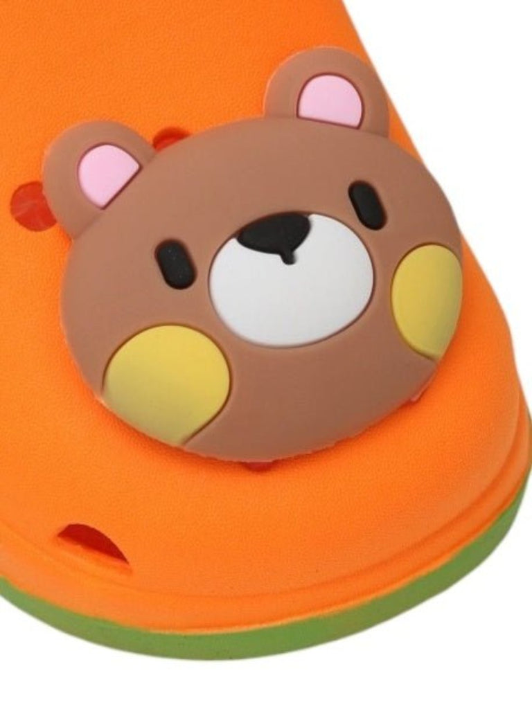 Close-up of the teddy bear face on the vibrant orange clogs, highlighting the playful design.