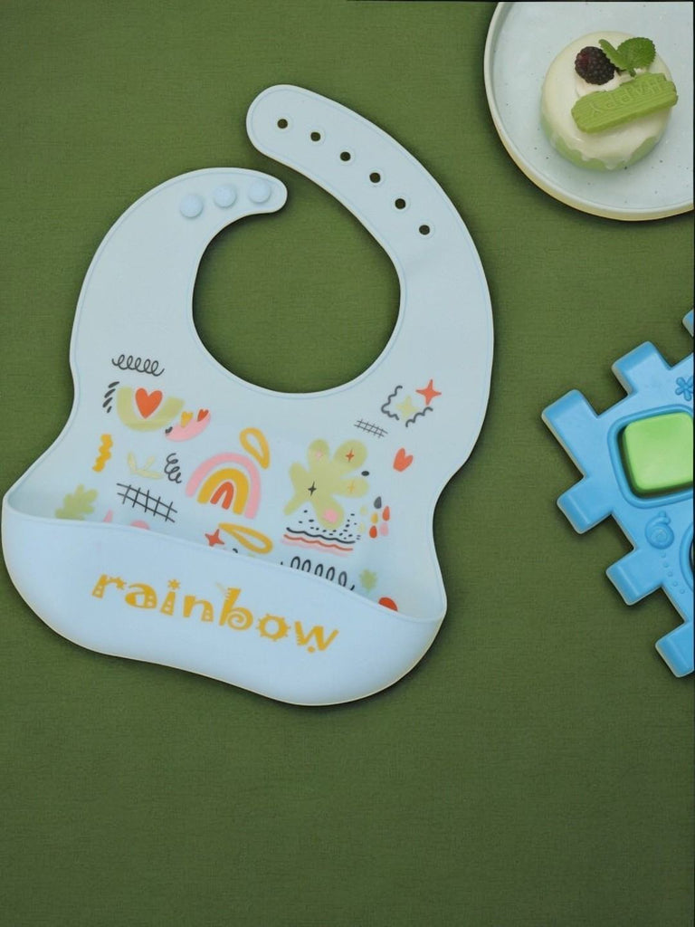 Creative display of the Cheerful Rainbow Doodle Silicone Baby Bib in a playful setting.