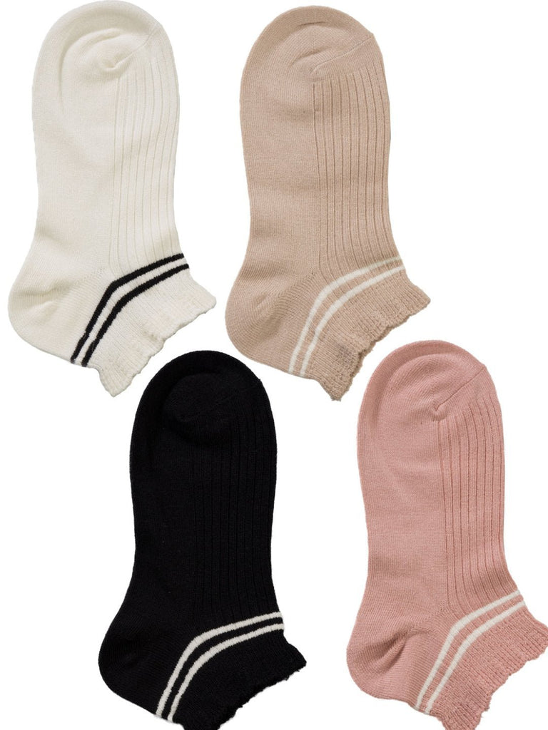 Four pairs of socks in neutral tones – black, beige, white, and pink – laid out flat with soft ruffle cuffs and striped details.
