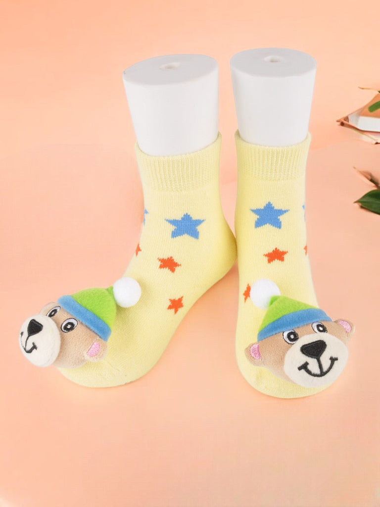 Kids' yellow socks with blue and red stars and plush bear toy detail creative view