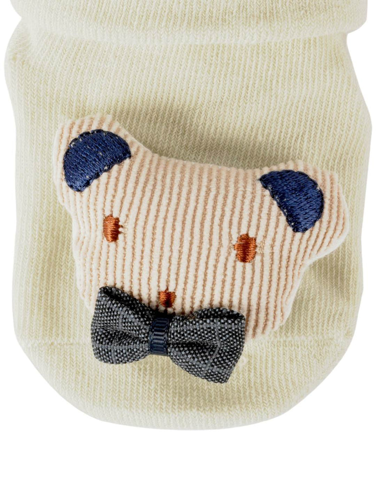 Closeup view of baby’s cream teddy bear-themed socks with an adorable bow tie accent.