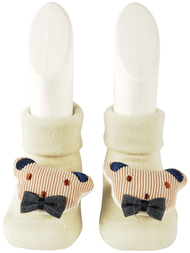 Front view of baby’s cream-colored socks featuring a cute teddy bear face with a bow tie.