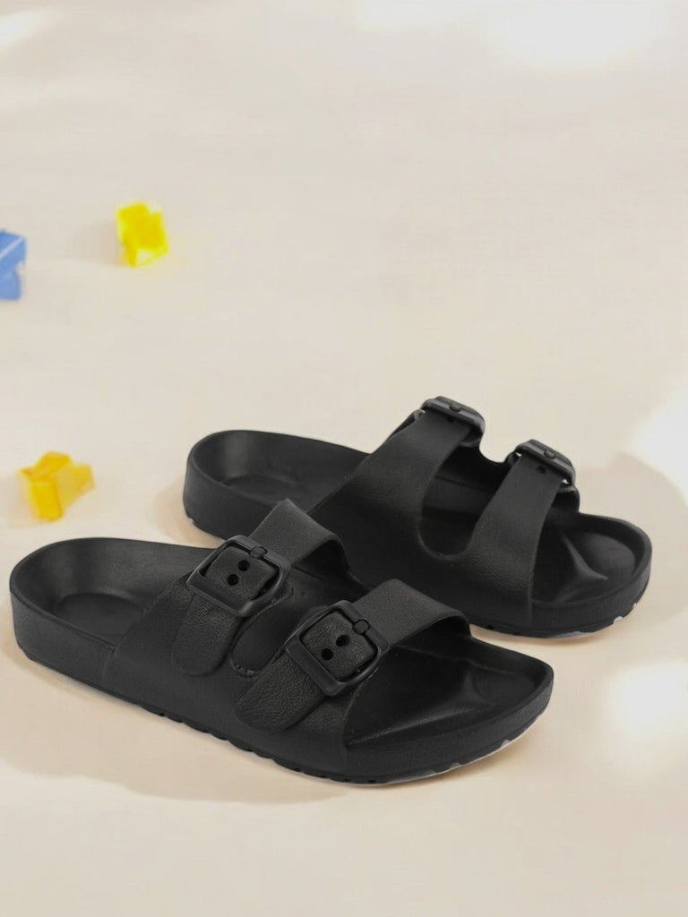 Creative view of black double buckle slides for boys displayed on a wooden surface.