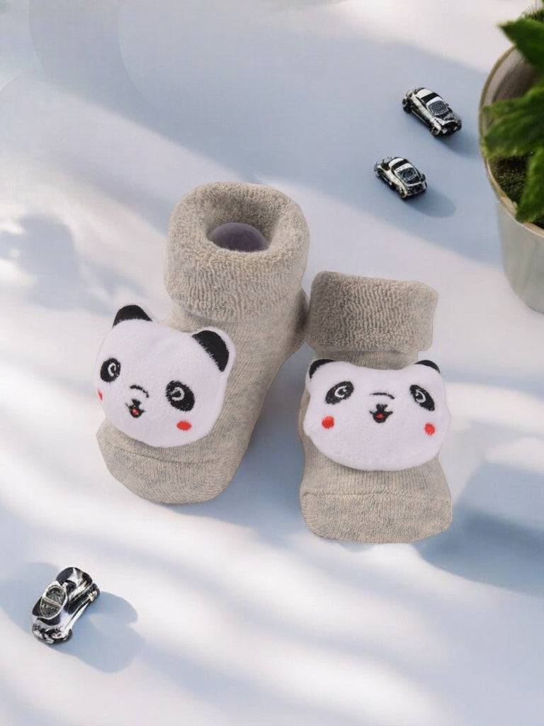 Creative display of grey baby booties with 3D panda face design.