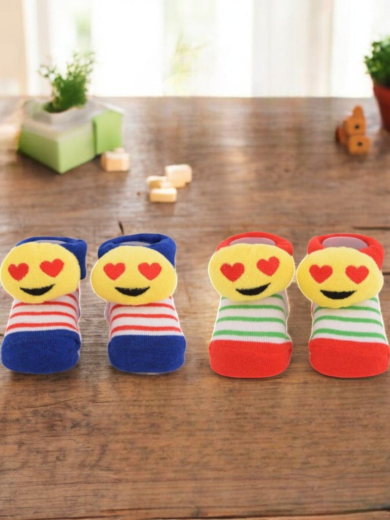 Heart-Eyes Emoji Plush Socks – Striped Combo Pack featuring playful emoji design with vibrant red, blue, and green stripes, displayed creatively on pink background.