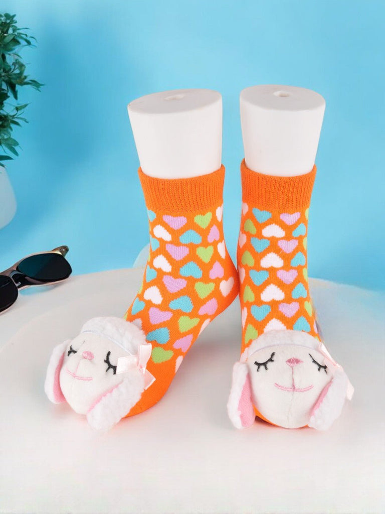 Playful toddler socks with lamb stuffed toy in orange with heart patterns - creative view.