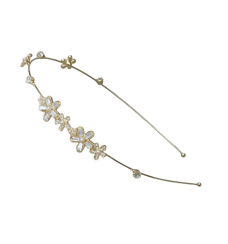 A close-up of Yellow Bee's golden hairband, highlighting the delicate faux pearl flowers and shiny metallic finish.
