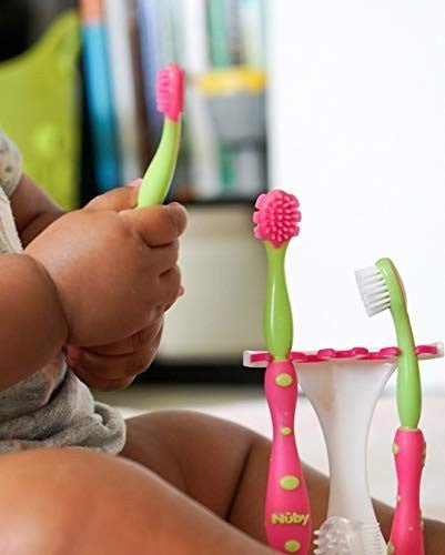 Baby holding Nuby Oral Care Set (Pink) toothbrush.