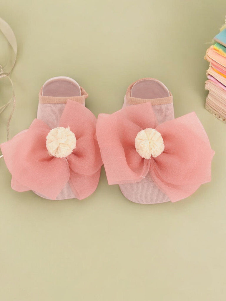 Pair of peach-colored socks with a large decorative bow and flower for children - creative view.