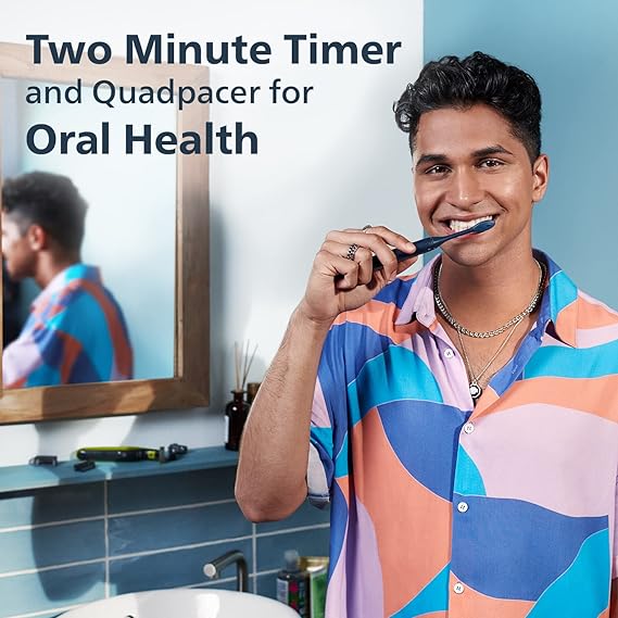 A person smiling while using the Philips One by Sonicare electric toothbrush in navy blue, demonstrating its ease of use.