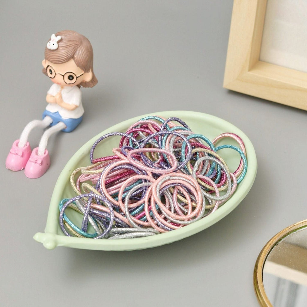 Styled image featuring Yellow Bee's glitter elastic hair ties with an adorable figurine, perfect for gifting.