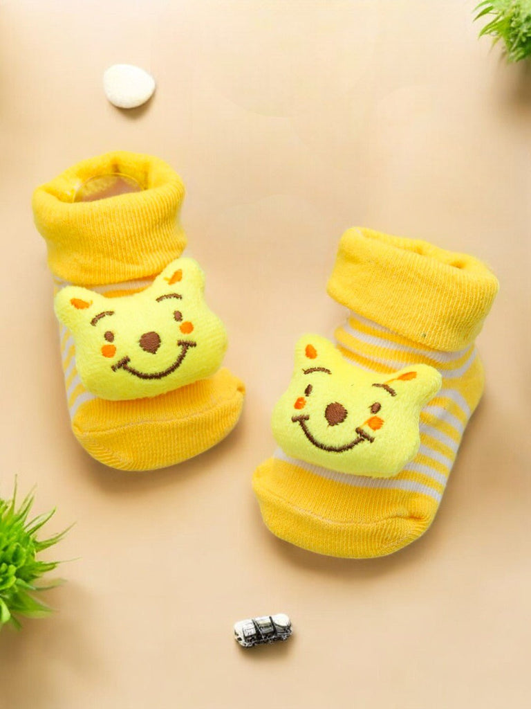 Creative display of yellow baby booties featuring a cheerful 3D bear design, ideal for keeping baby feet warm and cozy.