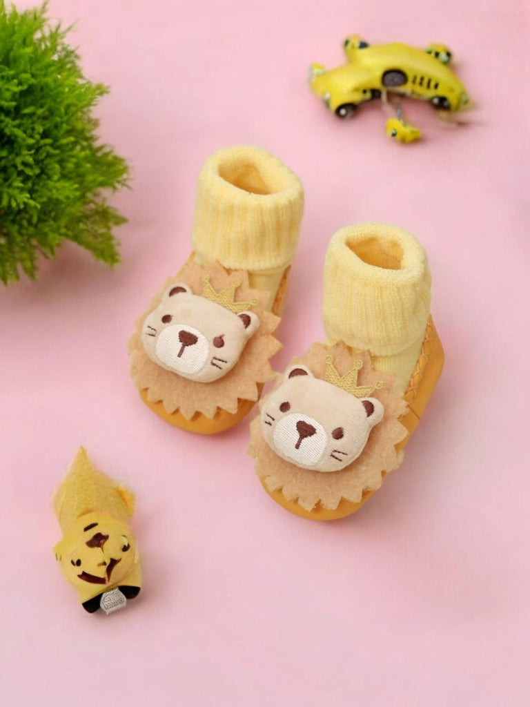 Yellow baby moccasin socks with adorable lion design in a creative display view.