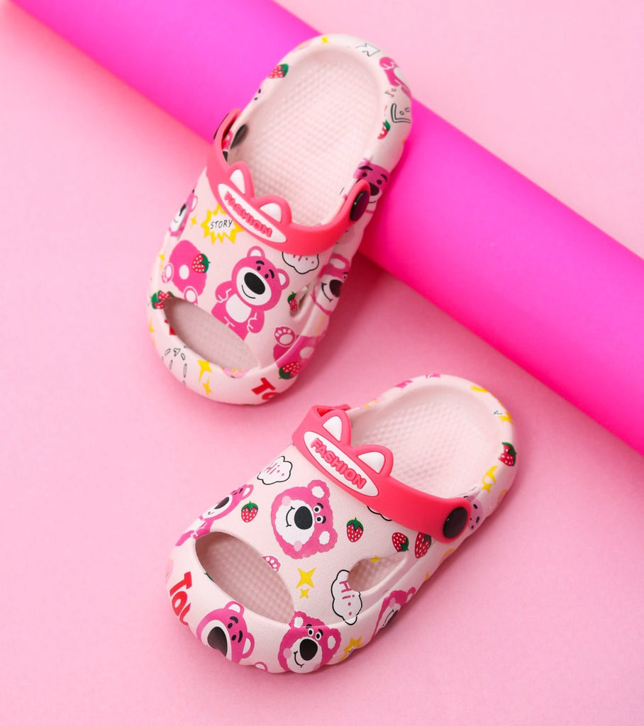 Kids' pink sandals with bear and strawberry prints on a vibrant background.