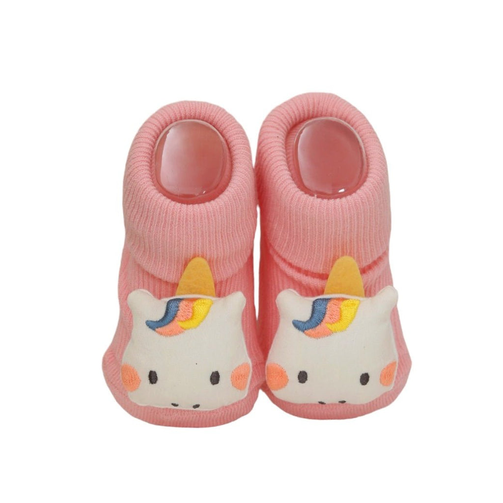 Pair of pink unicorn socks for baby girls set on a cozy backdrop