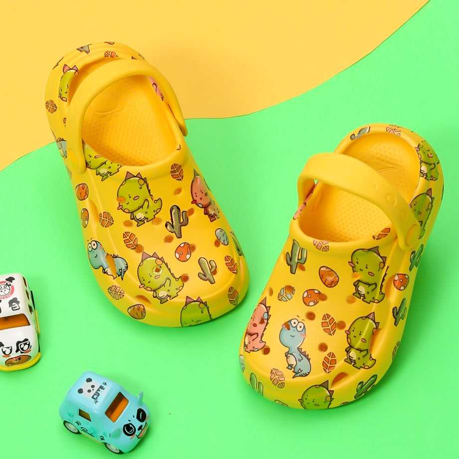 Jurassic Joy" Dino Print Yellow Clogs for Boys by Yellow Bee with vibrant desert backdrop.