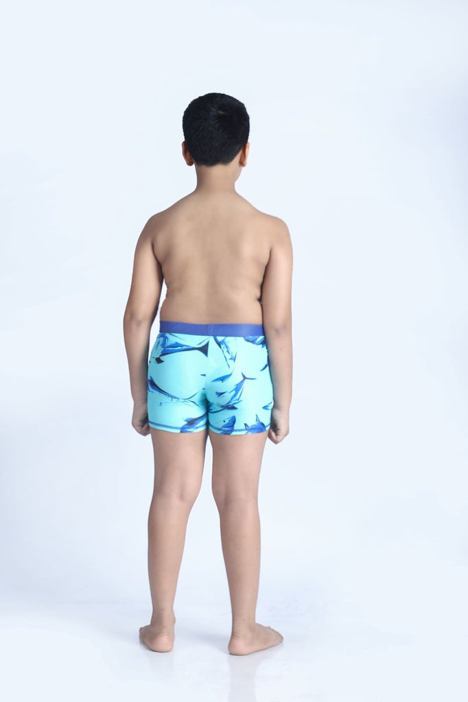 Back view of boy in aqua shark print swim shorts, ready for summer fun