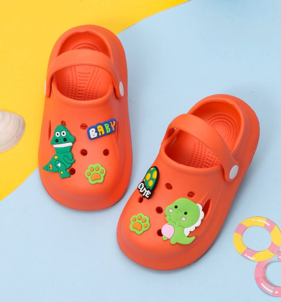 Adorable baby dino-decorated orange clogs for boys, showcased on a playful background