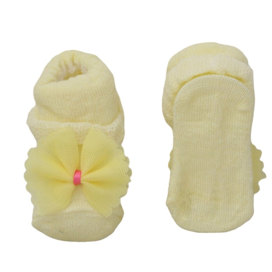 Bottom view of yellow baby girl socks with bow detail, highlighting the non-slip texture.