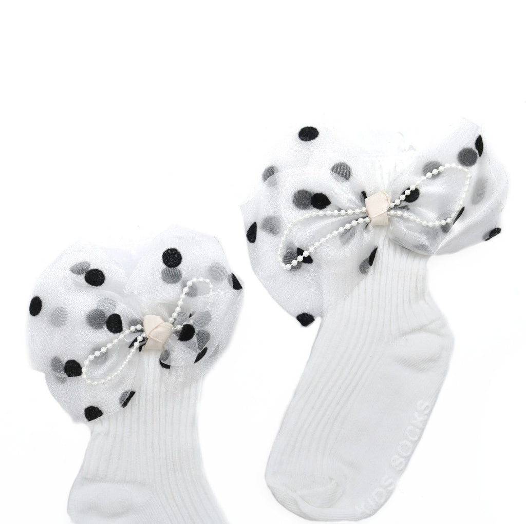 Close-up of white kids' socks with bow and polka dots, showcasing the intricate pearl details.