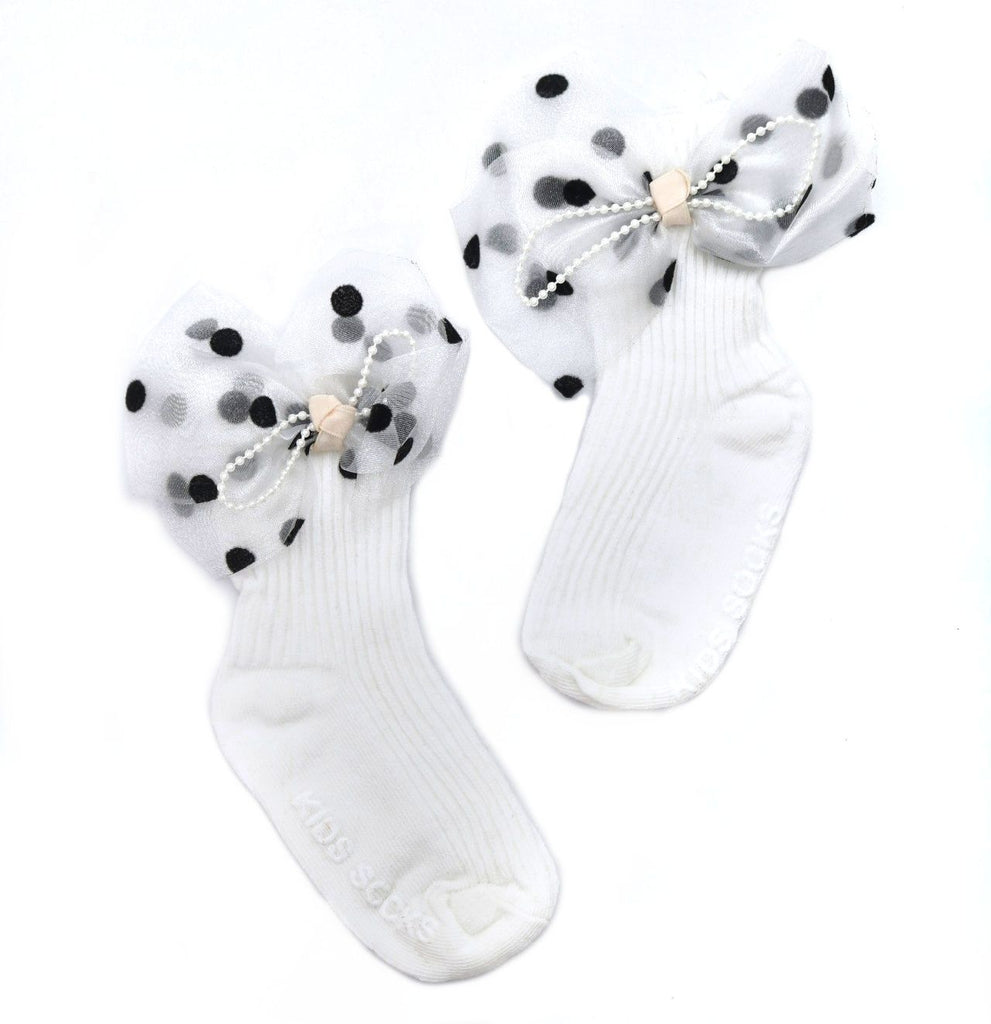 Pair of white children's socks with black polka dot bow and pearl decoration isolated on a white background.