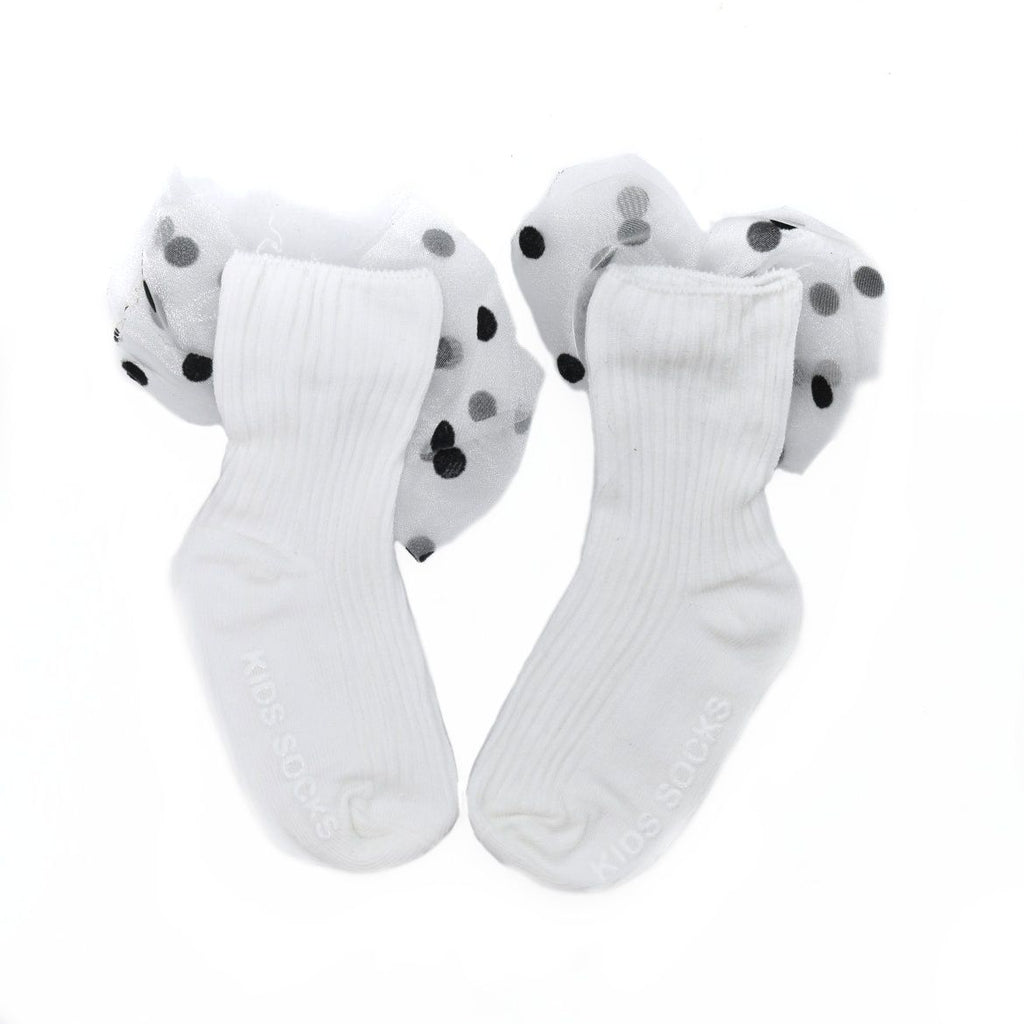 White socks with decorative bow for kids laid flat on white, highlighting the playful polka dot design.