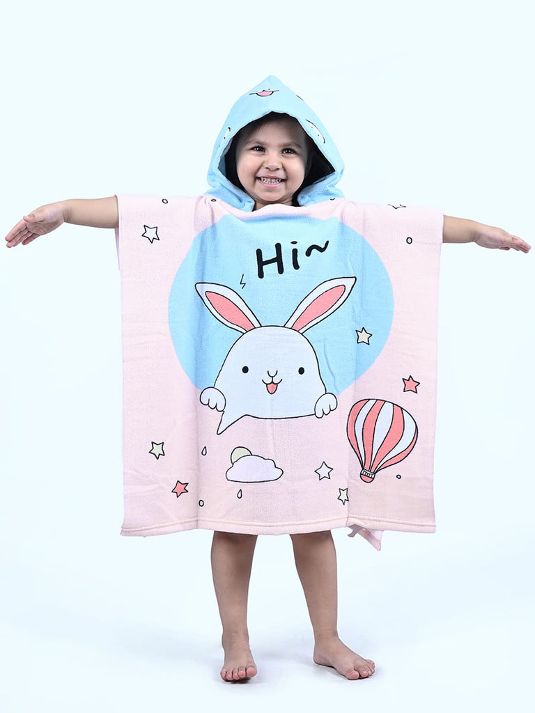 Child smiling in a Yellow Bee bunny hooded poncho towel in pink and aqua with a playful design