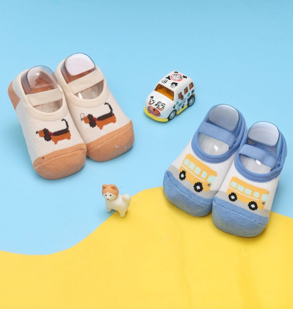 Two pairs of infant socks with a bus and puppy design in a playful setting.