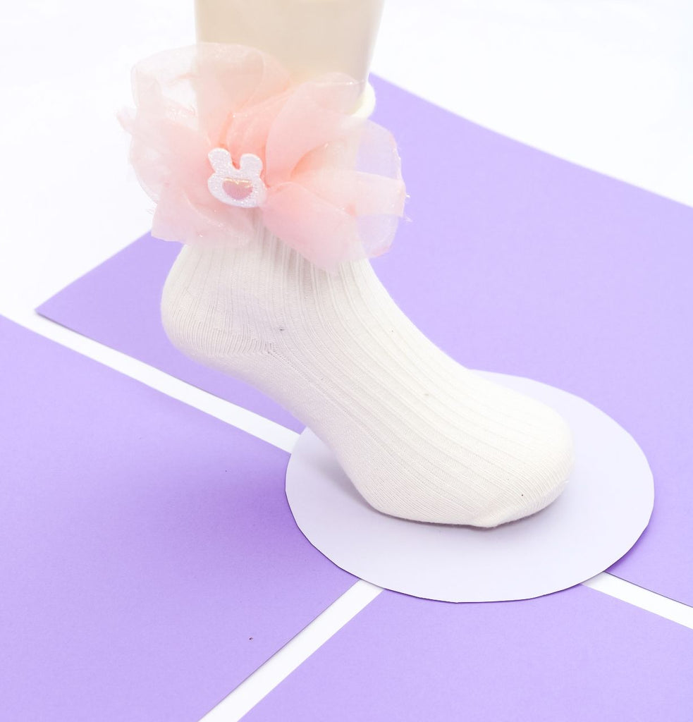Peach bow detailed sock on a child's foot with a playful tulle accent