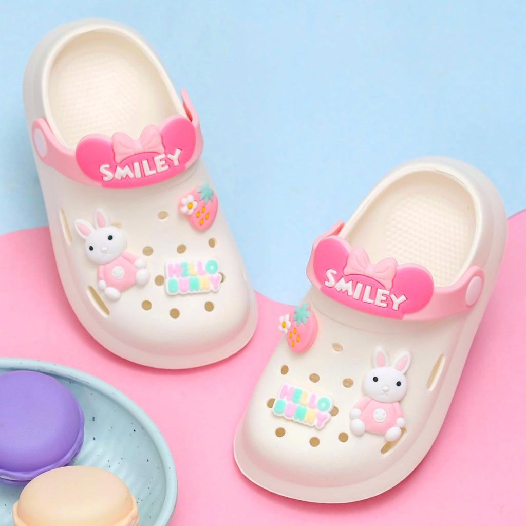 Pair of toddler's clogs in soft beige with pink bunny and smiley details.