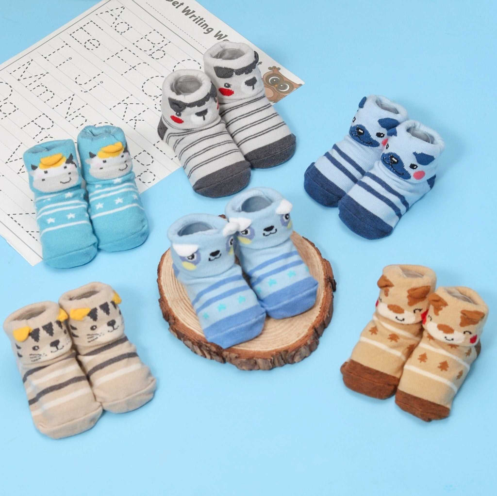 Animal-themed anti-skid socks set for baby boys displayed with toys and storybook.
