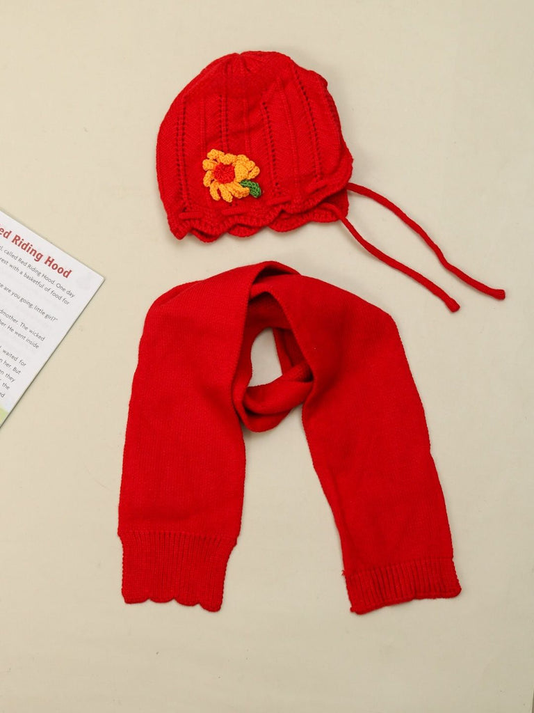 Girl's red knitted wool beanie with flower applique on a display stand.