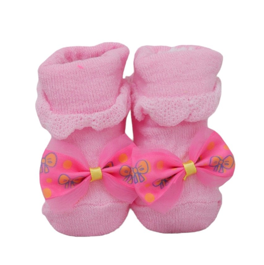 Pink baby socks featuring a polka-dot bow and butterfly motifs on a soft fabric.