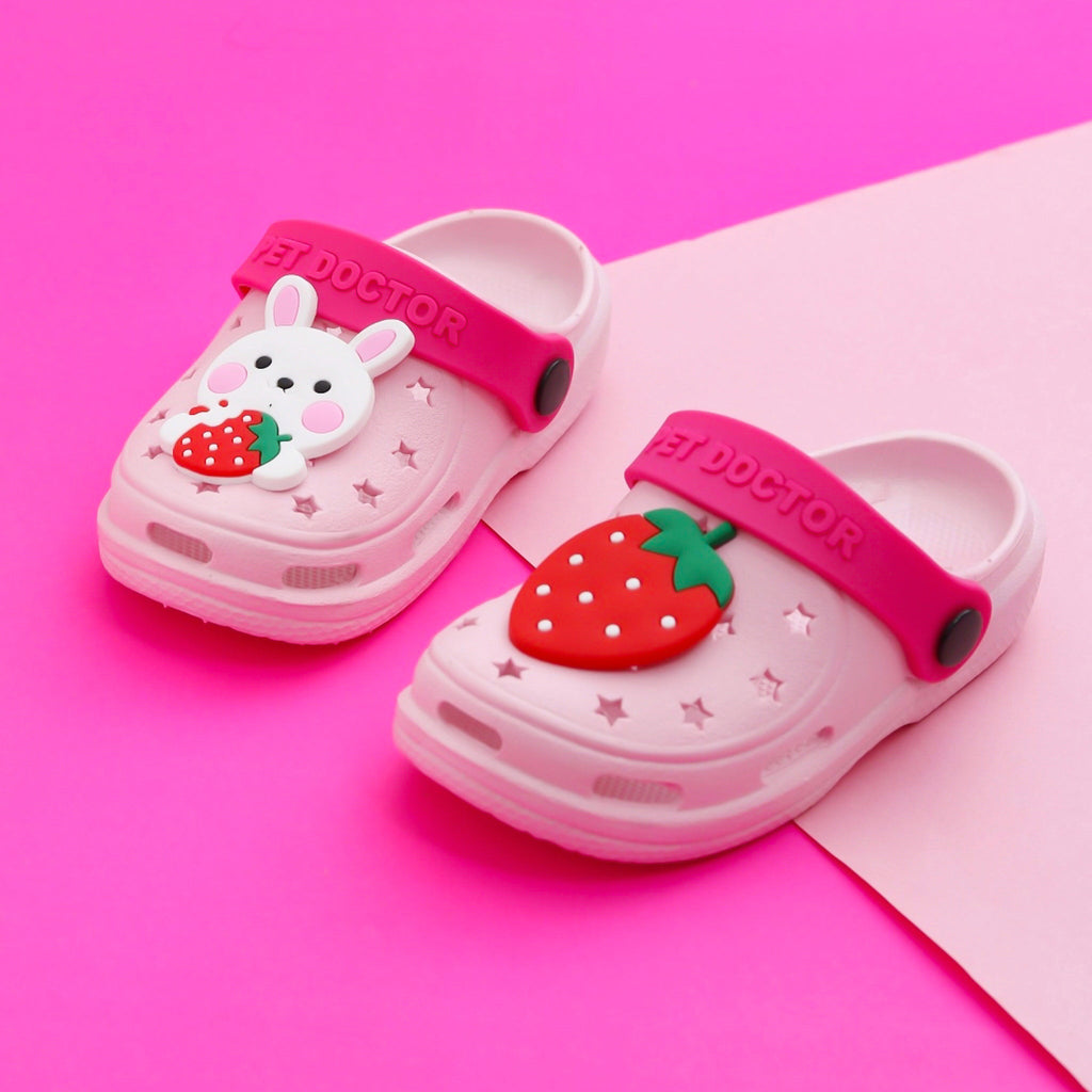 Pair of pink kids' clogs with bunny and strawberry motifs on a vibrant pink backdrop