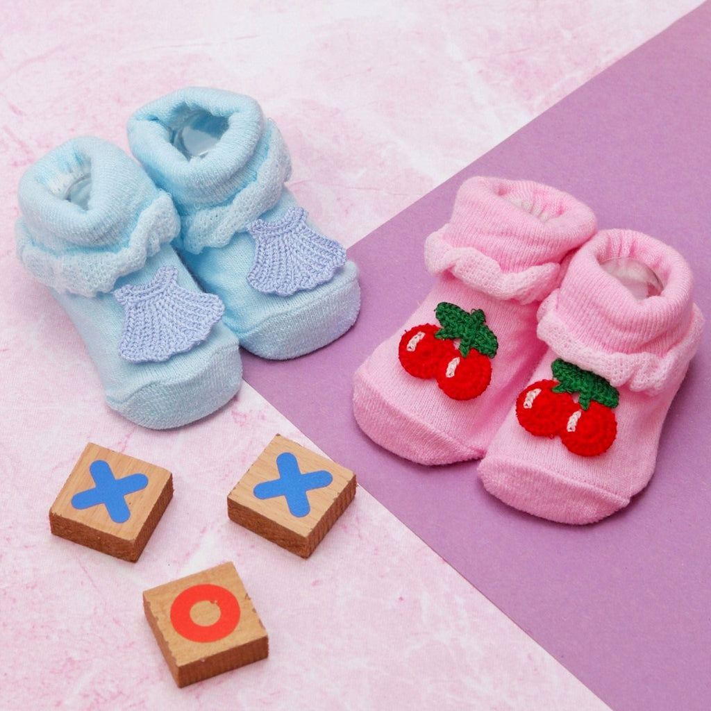 Baby girls' pink cherry-patterned and blue shell-patterned socks set on a playful background