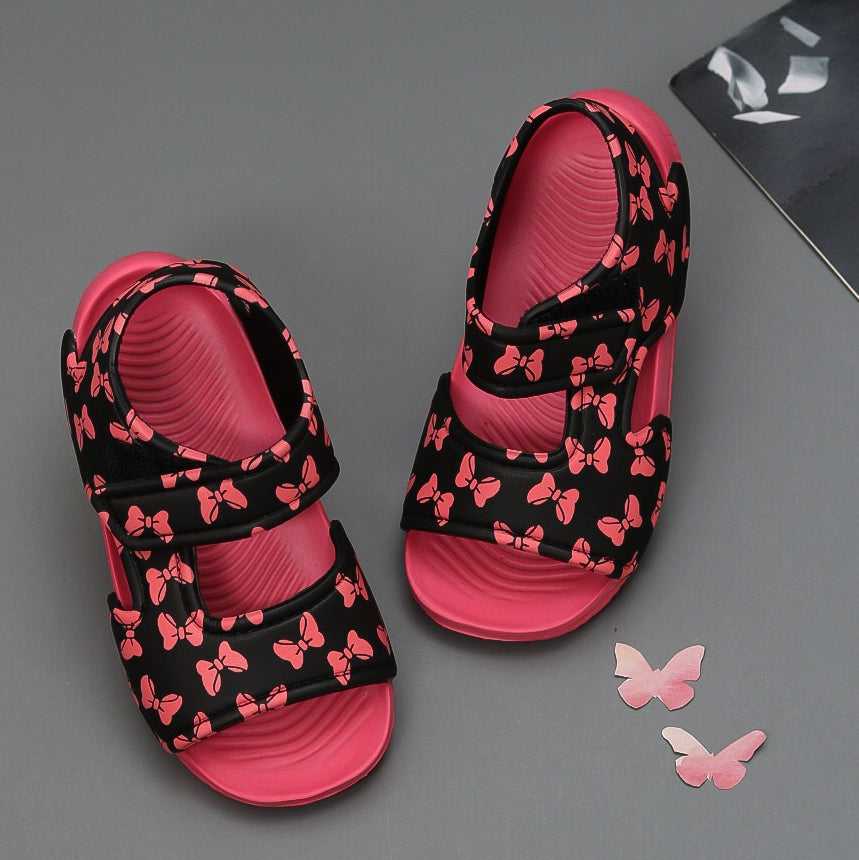 Stylish black sandals with pink bow print for kids on a grey background