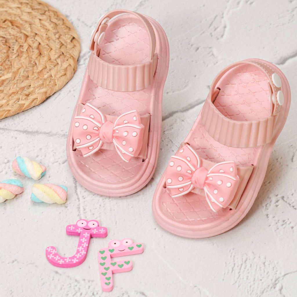 Cute pink bow detail sandals with a textured design, perfect for a stylish child's summer outfit.