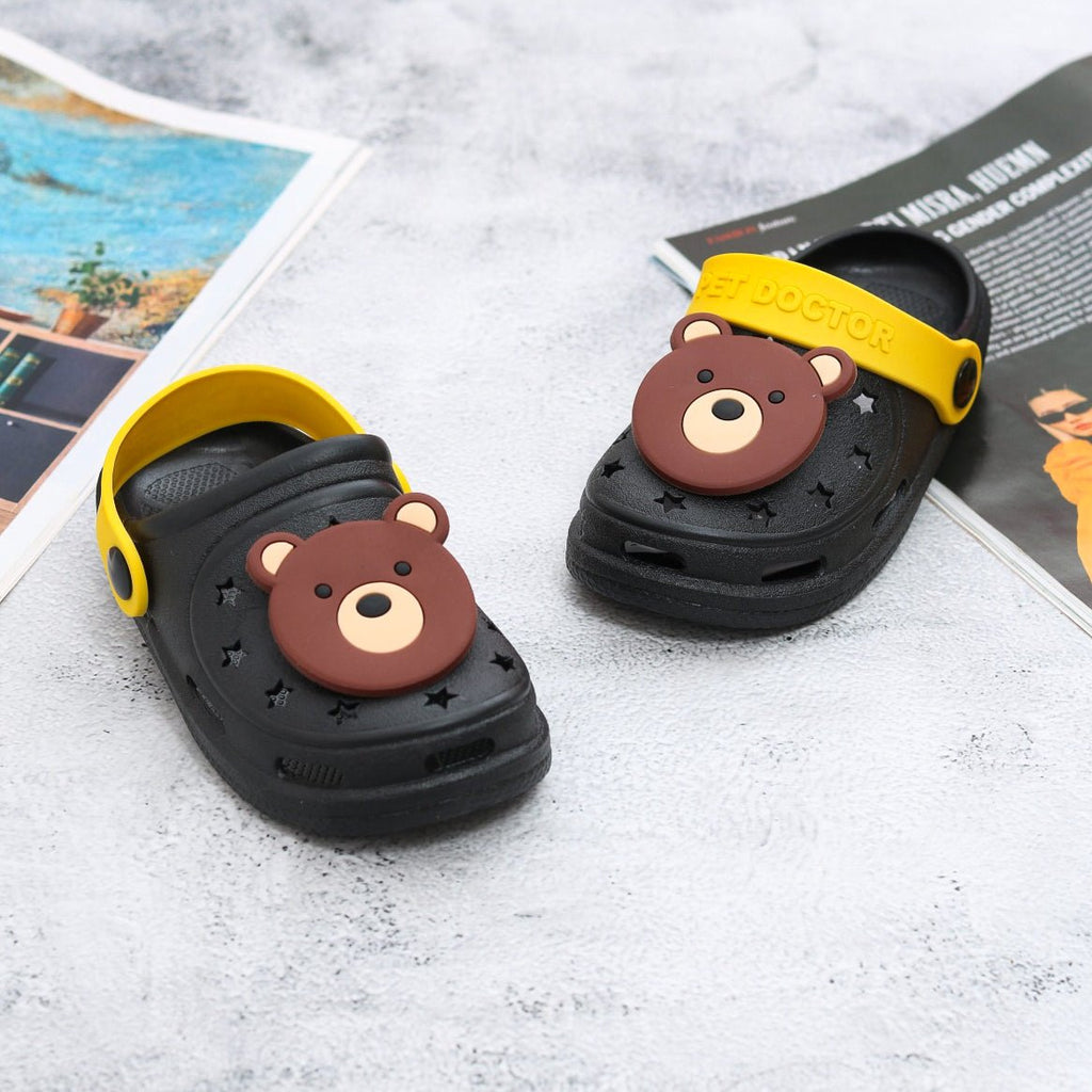 Top view of black and yellow toddler clogs with a cheerful bear motif against a white background.