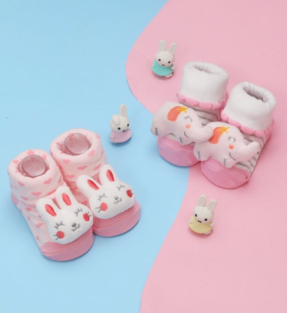 Pair of baby socks with elephant and bunny stuffed toy designs by Yellow Bee, presented with cute bunny figurines on a pastel background.