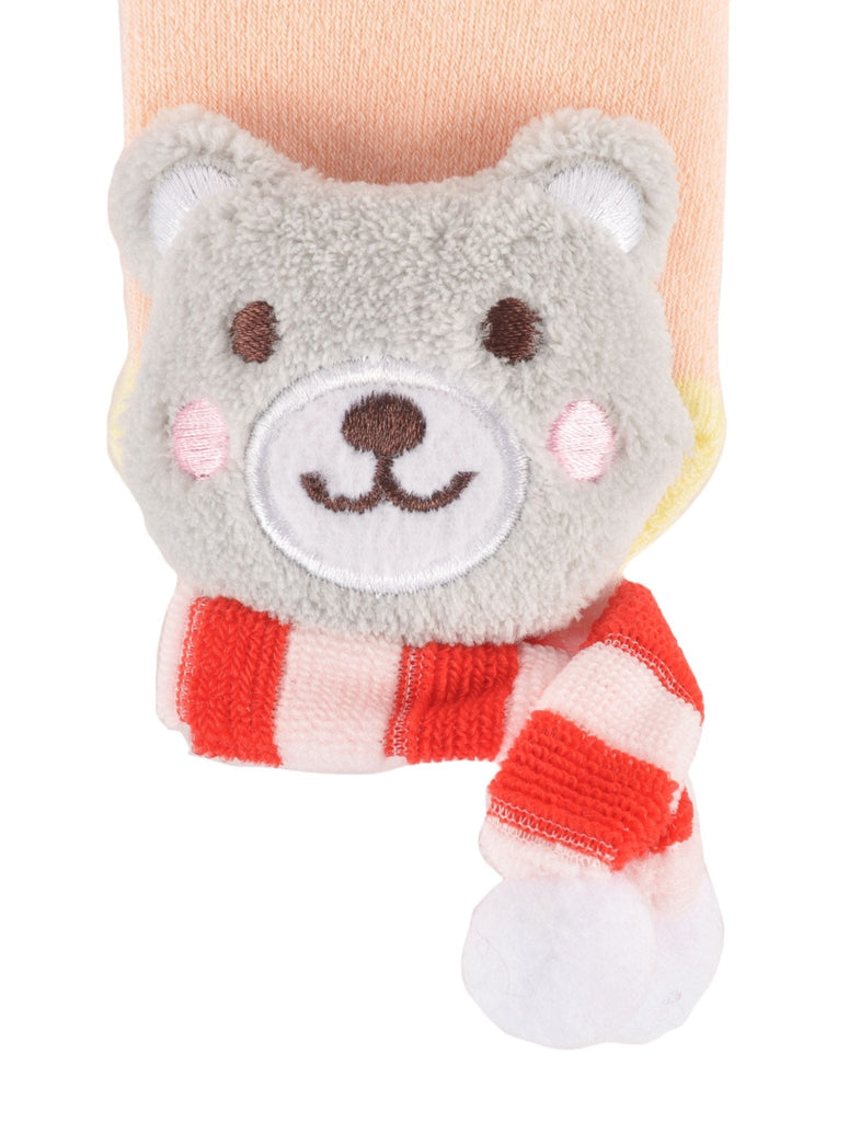 Close-up of the teddy bear stuffed toy on peach toddler sock with soft stripes