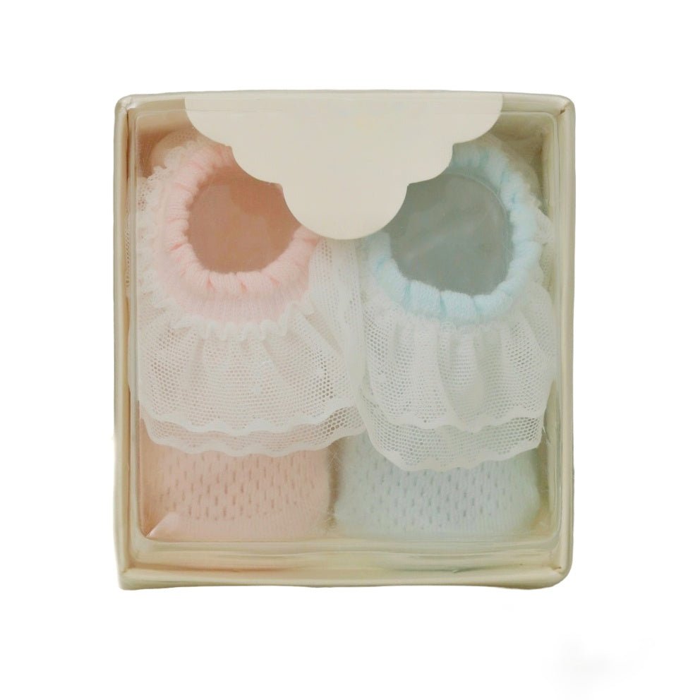 Pink and blue frilly leather socks for baby girls packaged in a clear gift box