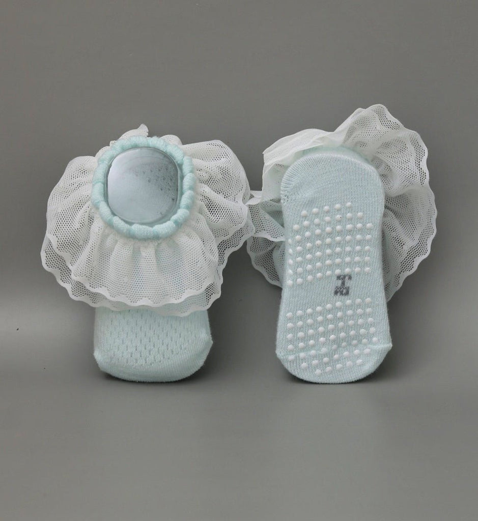 Pair of baby girl's blue leather socks with non-slip dots and white frill - bottom view