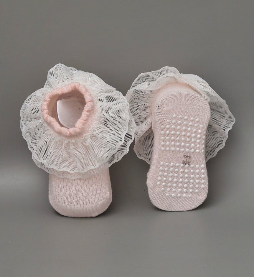 Baby girl's pink leather socks with white frill and anti-skid soles - top view.